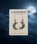 Pair of earrings on a Cumberland Creations card against a wooden background