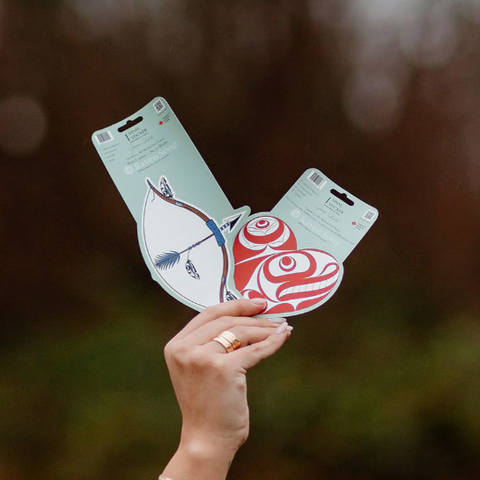 Hand holding a card with a design against a blurred natural background