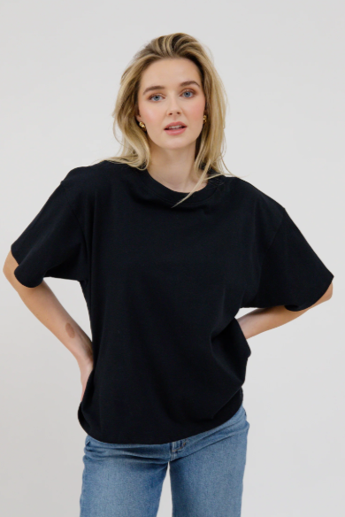 Woman wearing a black oversized sweater and blue jeans on a white background