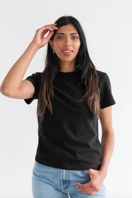 Woman wearing a black t-shirt and light blue jeans against a white background