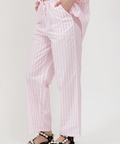 Person wearing pink striped pajama set with black sandals on a white background