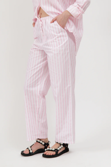 Person wearing pink striped pajama set with black sandals on a white background