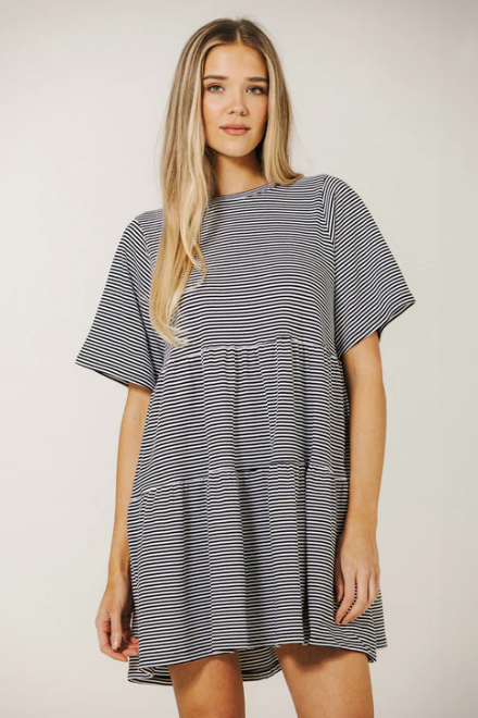 Woman wearing a black and white striped dress against a plain background