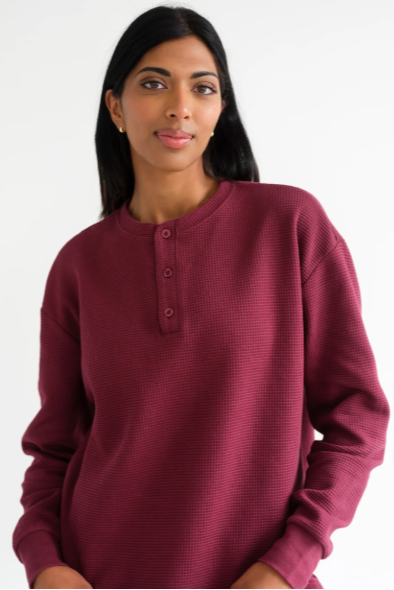Woman wearing a burgundy long-sleeve shirt on a white background