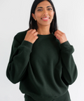 Woman wearing a dark green sweatshirt against a white background