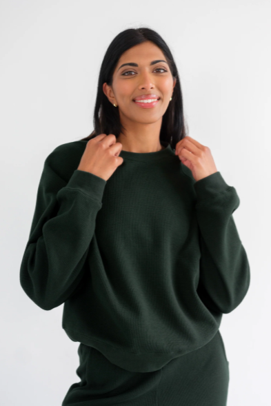 Woman wearing a dark green sweatshirt against a white background
