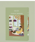 A 1000-piece jigsaw puzzle box by classycards titled 'I'M BUSY READING', featuring a cozy illustration of a person reading in a yellow armchair by a window with autumn leaves.