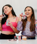 Two women in a kitchen holding drinks and smiling.