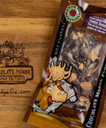 A 10g bag of Chocolate Moose Fudge Factory Chocolate Chip Cookie Dough fudge, placed on a wooden surface next to a laser-engraved logo of the same brand.