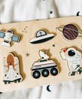 Wooden puzzle with space-themed pieces on a light fabric background