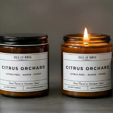 Two candles labeled 'Isle of Rose Citrus Orchard' on a dark background