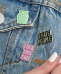 Three pins on a denim jacket: 'Work hard, sweat often', 'I Hate People', and 'Fuck this shit'.
