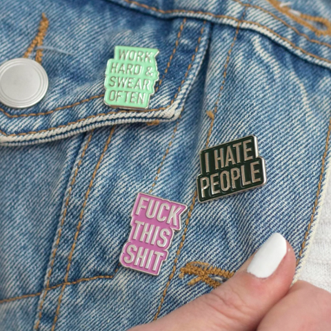 Three pins on a denim jacket: 'Work hard, sweat often', 'I Hate People', and 'Fuck this shit'.