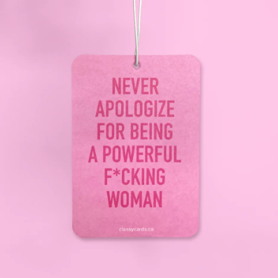 Pink air freshener with text held by a hand against a pink background
