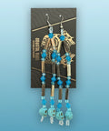 Pair of gold and turquoise beaded earrings on a display card against a wooden background