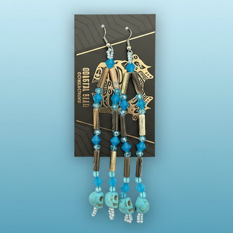 Pair of gold and turquoise beaded earrings on a display card against a wooden background
