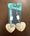 Shell earrings on a card with 'Coastal Hero Collective' branding on a wooden surface.