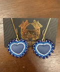 Blue heart-shaped earrings on a card with a gold design, placed on a wooden surface.