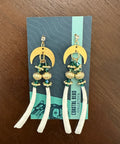 Pair of earrings on a display card with a wooden surface background