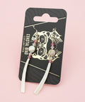 Decorative hair clip on a branded card with a dark background