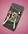 Set of earrings on a branded card with a wooden surface background