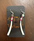 Set of earrings on a branded card with a wooden surface background