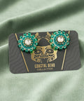 Pair of earrings on a branded card against a wooden surface