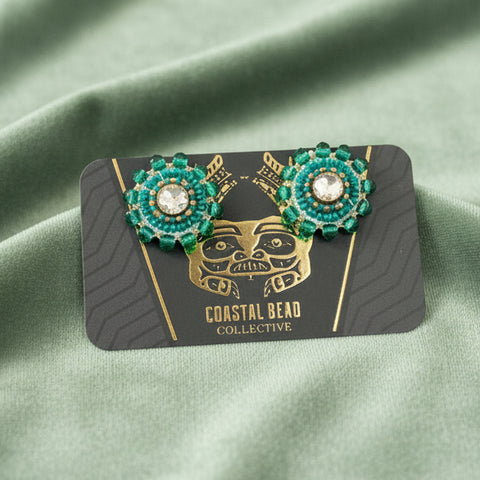 Pair of earrings on a branded card against a wooden surface