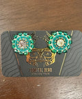 Pair of earrings on a branded card against a wooden surface