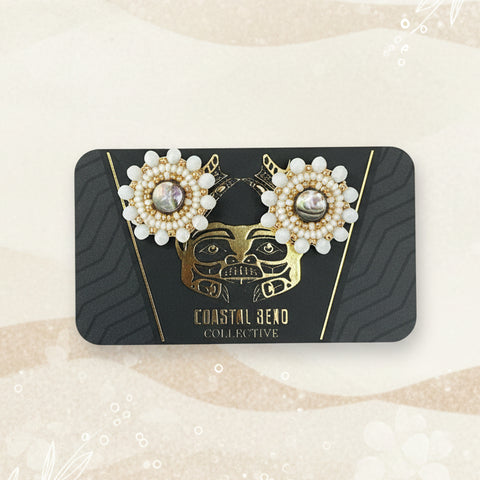 Pair of pearl earrings on a branded card against a wooden surface