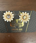 Pair of pearl earrings on a branded card against a wooden surface