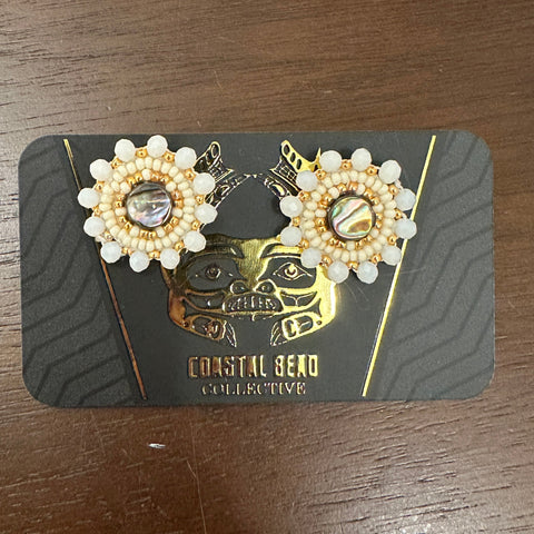 Pair of pearl earrings on a branded card against a wooden surface