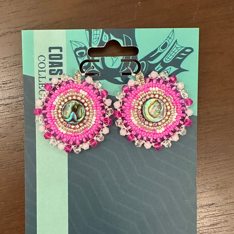 Pair of pink earrings on a card with 'Coast Collection' branding on a wooden surface.