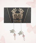 Pair of earrings on a card with a decorative design, placed on a wooden surface.