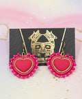 Pink heart-shaped earrings on a dark wooden surface