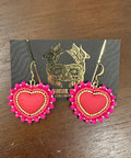 Pink heart-shaped earrings on a dark wooden surface