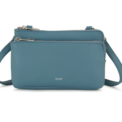 Blue crossbody bag with a visible brand logo on a white background