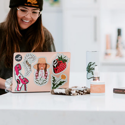 Person with a laptop covered in stickers on a desk