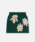 A dark green knit mini skirt featuring a pattern of large white daisy flowers with yellow centers, shown flat against a light gray background.