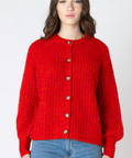Woman wearing a red knitted cardigan and blue jeans on a white background