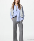 Woman wearing a light blue shirt, gray pants, and white sneakers on a white background