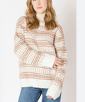 Woman wearing a patterned sweater and jeans on a plain background