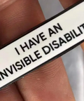 Badge with 'I have an invisible disability' text held between fingers