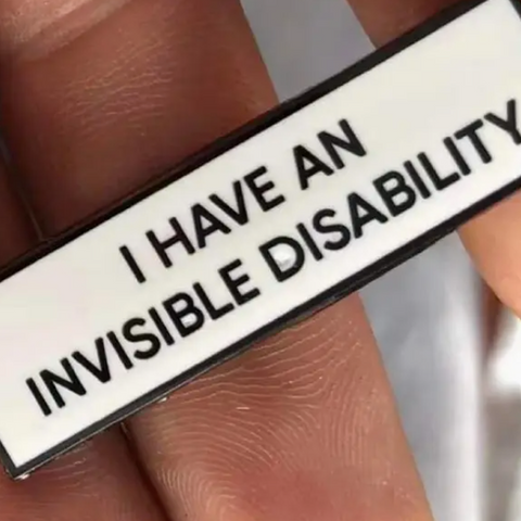 Badge with 'I have an invisible disability' text held between fingers