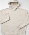 A light beige pullover hoodie with tonal embroidery on the chest reading 'I'M DOING MY FUCKING BEST' and a matching tonal sleeve graphic, laid flat on a light gray background.