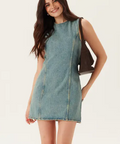 Woman wearing a denim dress holding a brown handbag on a white background