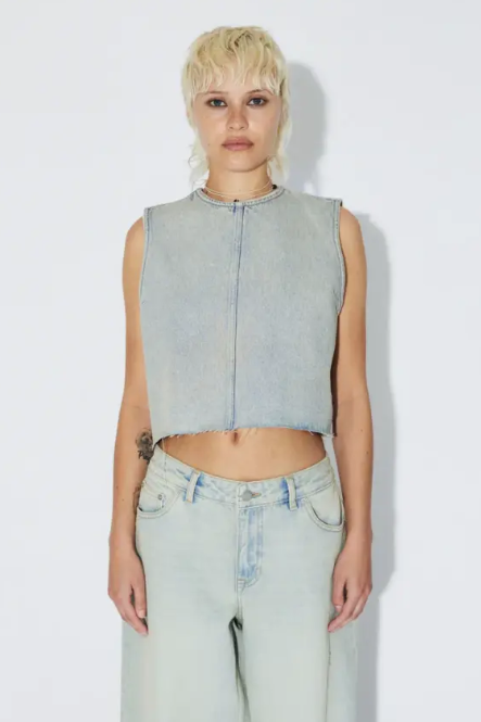 Person wearing a light blue sleeveless denim top and light blue jeans on a white background