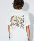 Person wearing a white t-shirt with abstract designs on the back, standing against a plain background.