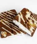 Chocolate bars with white drizzle and gold flakes on a white background