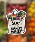 Sticker with 'SLUT for the Farmer's Market' text on a blurred market background